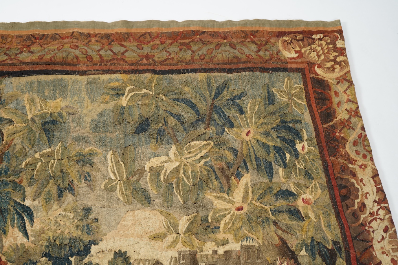 A mid to late 18th century French Aubusson tapestry of a bird, possibly a heron, within a tree lined verdure garden scene to a chateaux, with an ornate rust coloured contrasting tapestry border.201cm x 170 cm. Condition